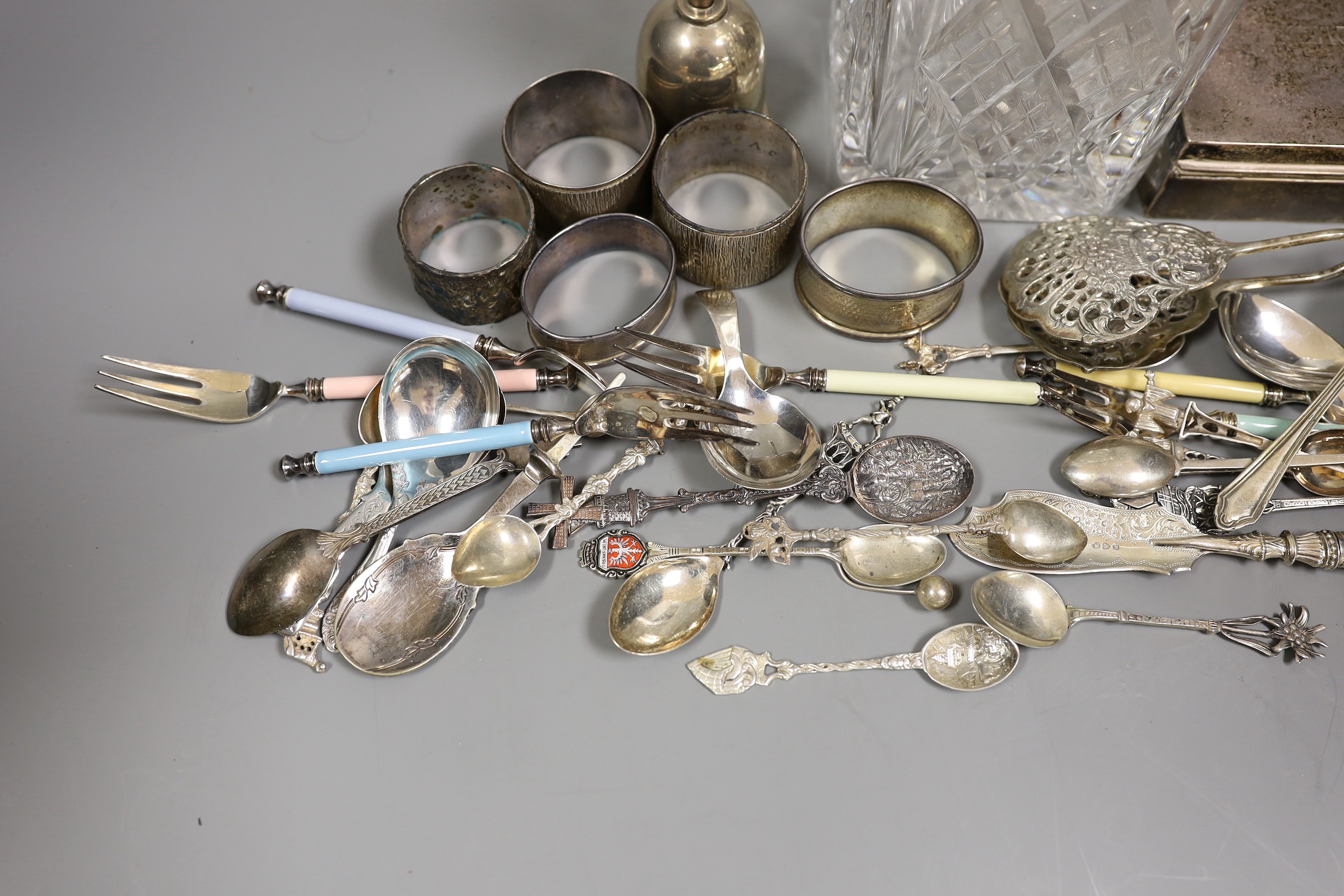 Mixed silver items etc. including a modern silver collared glass decanter, cigarette box, 800 standard white metal cake tongs, a white metal hand bell(lacking clapper), six plated Noritake tea forks, assorted minor silve